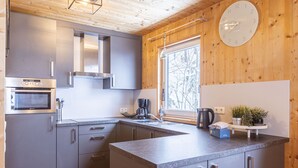 Une cuisine moderne avec des meubles gris, des appareils en acier inoxydable et une grande fenêtre.