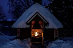 A cozy cabin with a snow-covered roof and a visible fireplace.