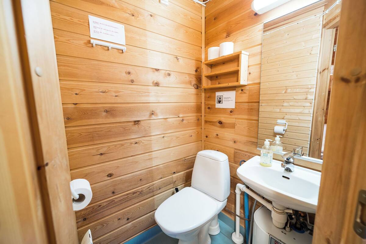 Un baño con paneles de madera, un inodoro, un lavamanos y un espejo.