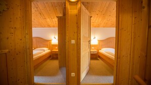 Una habitación de madera con dos camas, cada una con una mesita de noche y una lámpara de pared.