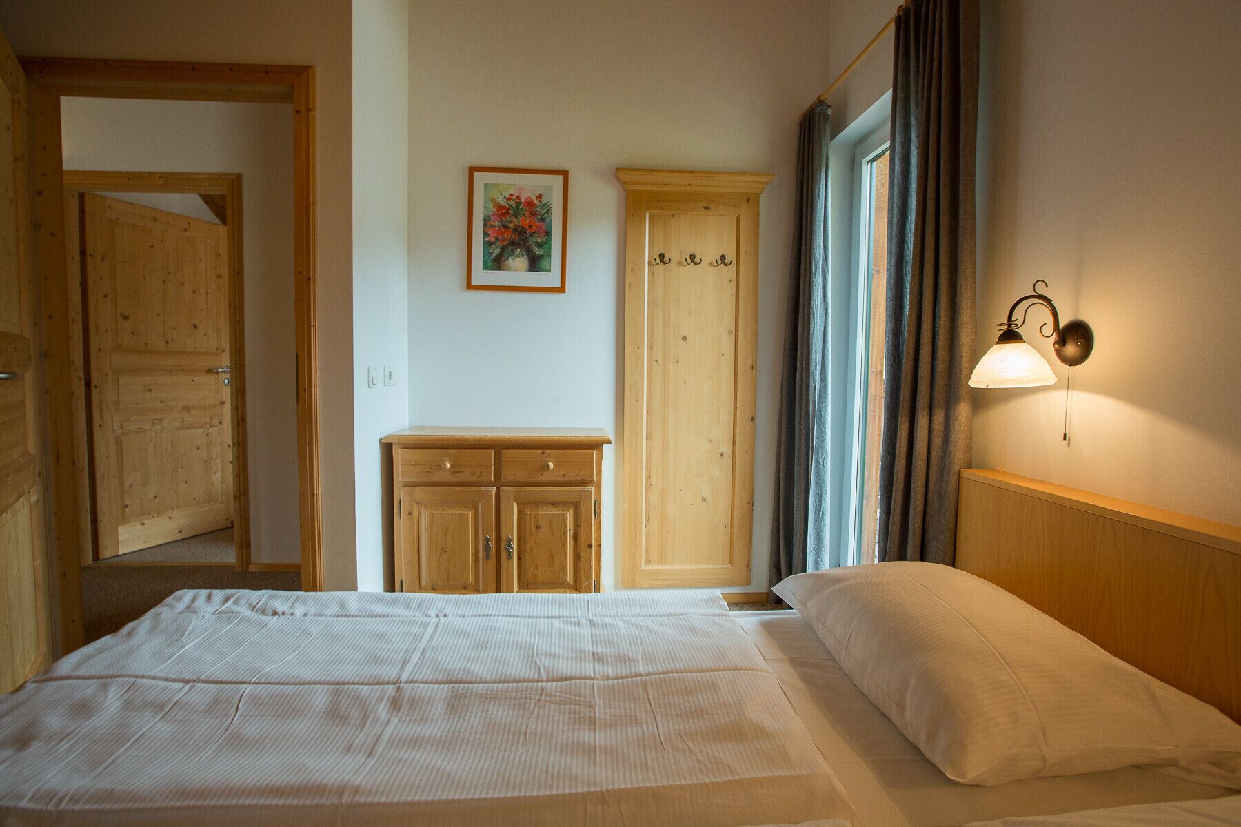 Ein Schlafzimmer mit einem Bett, einem Holzschrank und einer Wandlampe.