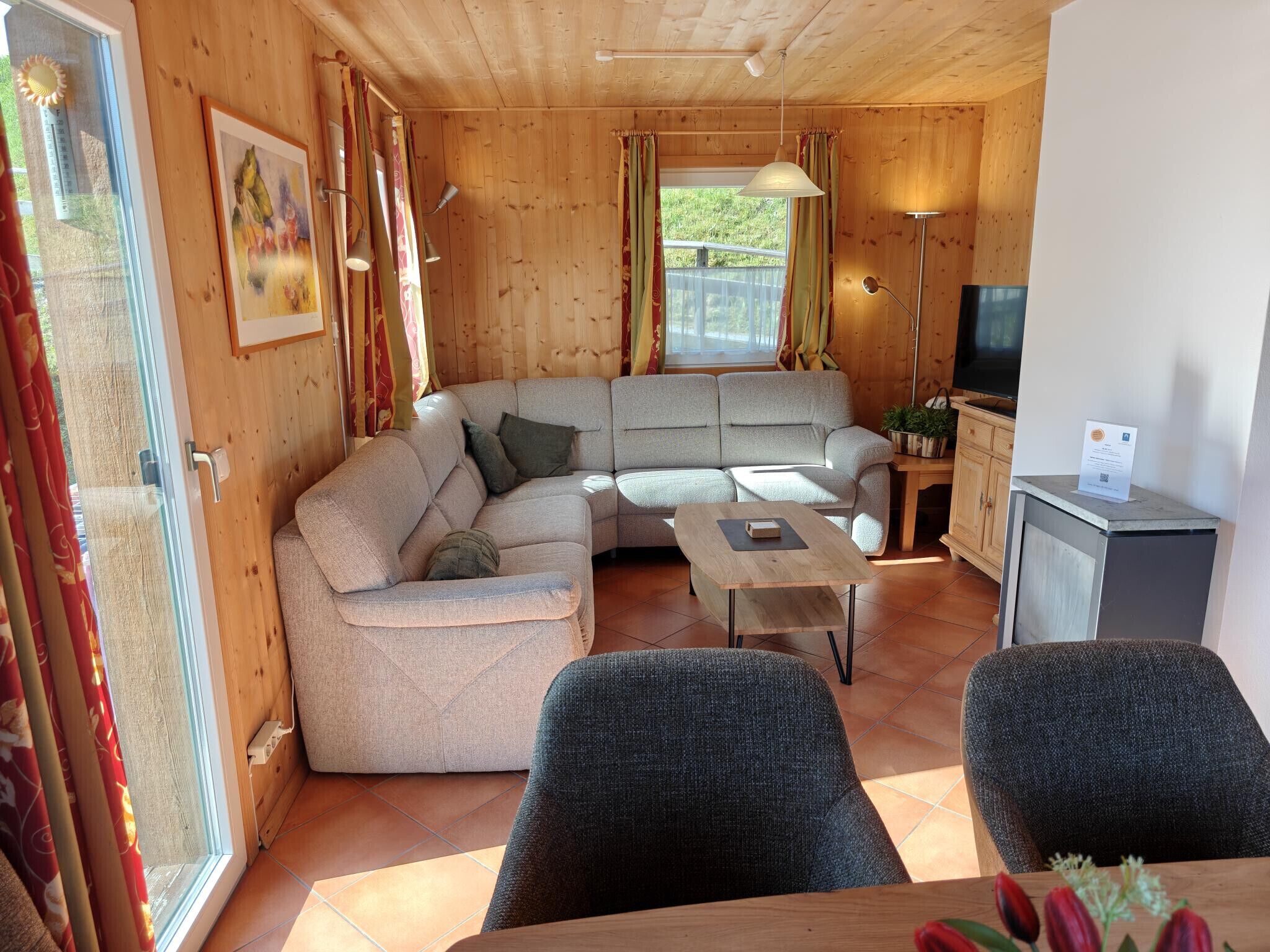 A wooden interior with a sofa, a table, and a television.