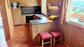 A kitchen with wooden cabinets, a built-in oven, a sink, and a window with a view of the landscape.