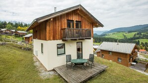 A wooden chalet with a balcony, a deck with outdoor furniture, and a view of a mountainous landscape. - Chalet # 56 with 3 BR for up to 6 people (Annaberg)