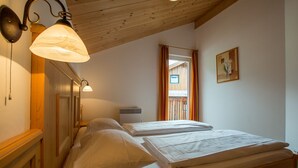 A bedroom with two beds, wooden ceiling beams, and a window with curtains. - Chalet # 56 with 3 BR for up to 6 people (Annaberg)