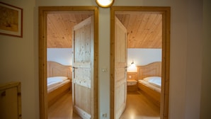 A room with two wooden beds, a wooden door, and a light fixture on the ceiling.