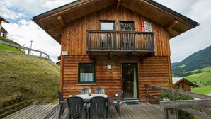 A wooden chalet with a balcony, a dining area with chairs and a table, and a sign indicating private property.
