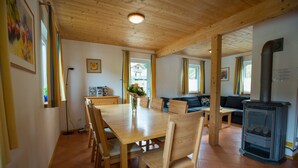 A cozy room with a wooden dining table, chairs, a sofa, and a fireplace.