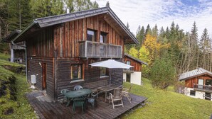 A wooden cabin with a balcony, a deck with outdoor furniture, and a view of a forested area. - Chalet # 22 with 3 BR for up to 6 people (Annaberg)