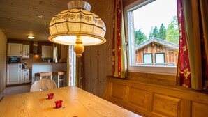 A wooden dining table with three red cups, a hanging lamp, and a window with curtains. - Chalet # 22 with 3 BR for up to 6 people (Annaberg)