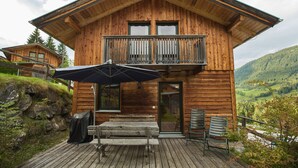 A wooden cabin with a balcony, a covered outdoor seating area, and a view of the surrounding landscape. - Chalet # 65 with 3 BR for up to 6 people (Annaberg)