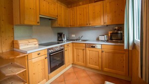 A compact kitchen with wooden cabinets, a built-in oven, a microwave, and a coffee maker. - Chalet # 65 with 3 BR for up to 6 people (Annaberg)