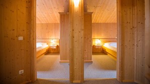A wooden room with two beds, each with a bedside table and lamp, and a mirror on the door. - Chalet # 65 with 3 BR for up to 6 people (Annaberg)