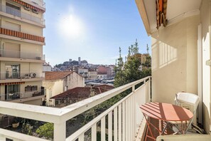Un balcón con mesa y silla, con vistas a un paisaje urbano que incluye edificios y una torre.