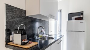 Una cocina moderna con encimera negra, pileta de acero inoxidable y refrigerador blanco.