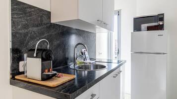 A modern kitchen with a black countertop, stainless steel sink, and a white refrigerator.