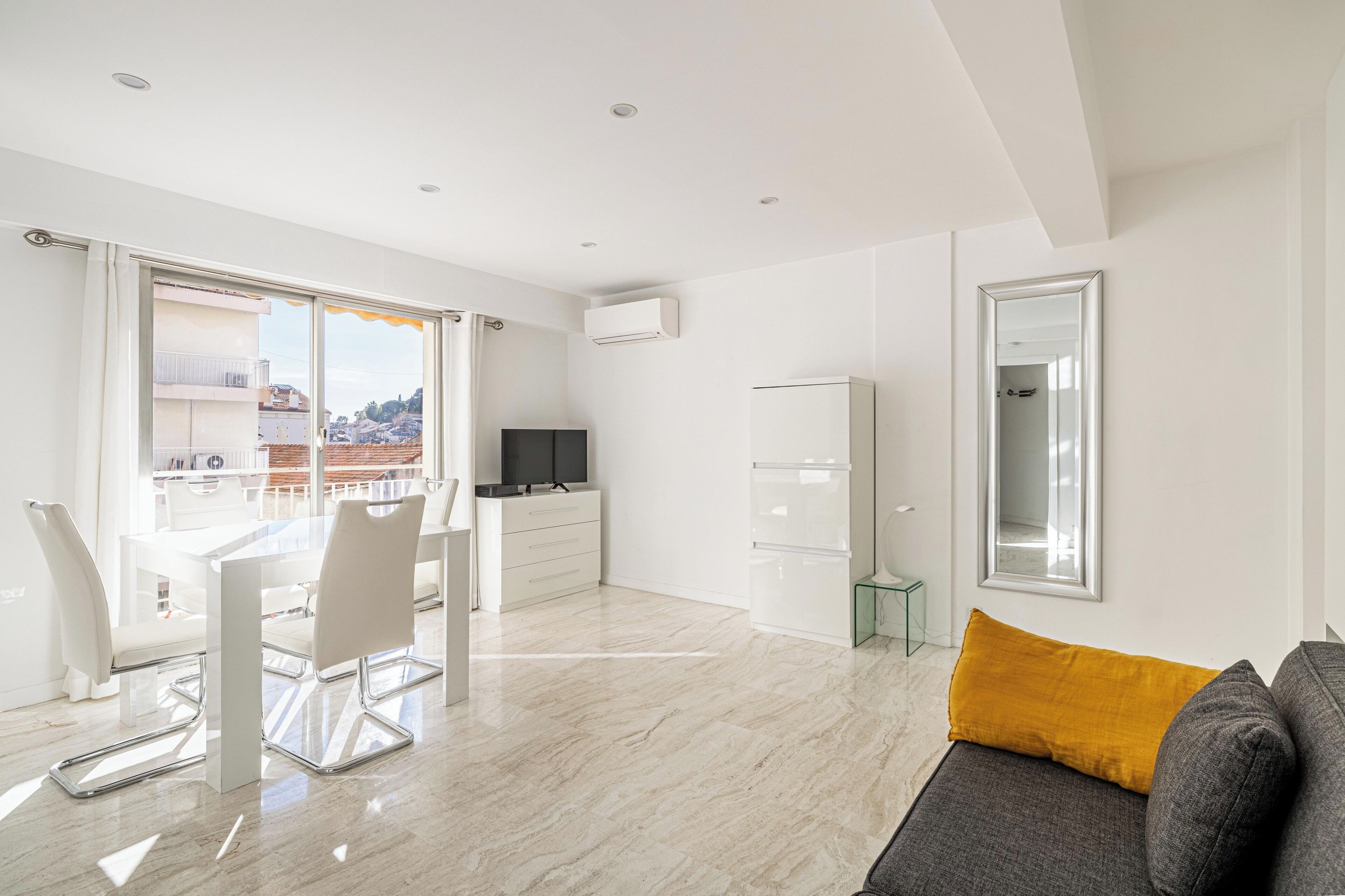 Un soggiorno moderno con zona pranzo, divano, televisore e balcone con vista sulla città.