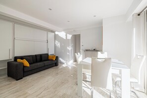 Una sala de estar moderna con sofá, mesa de comedor y zona de cocina.