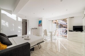 A modern hotel room with a bed, seating area, TV, and a balcony with a view.