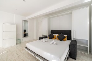 Un dormitorio moderno con una cama grande, un armario, un espejo y un aparador de vidrio.