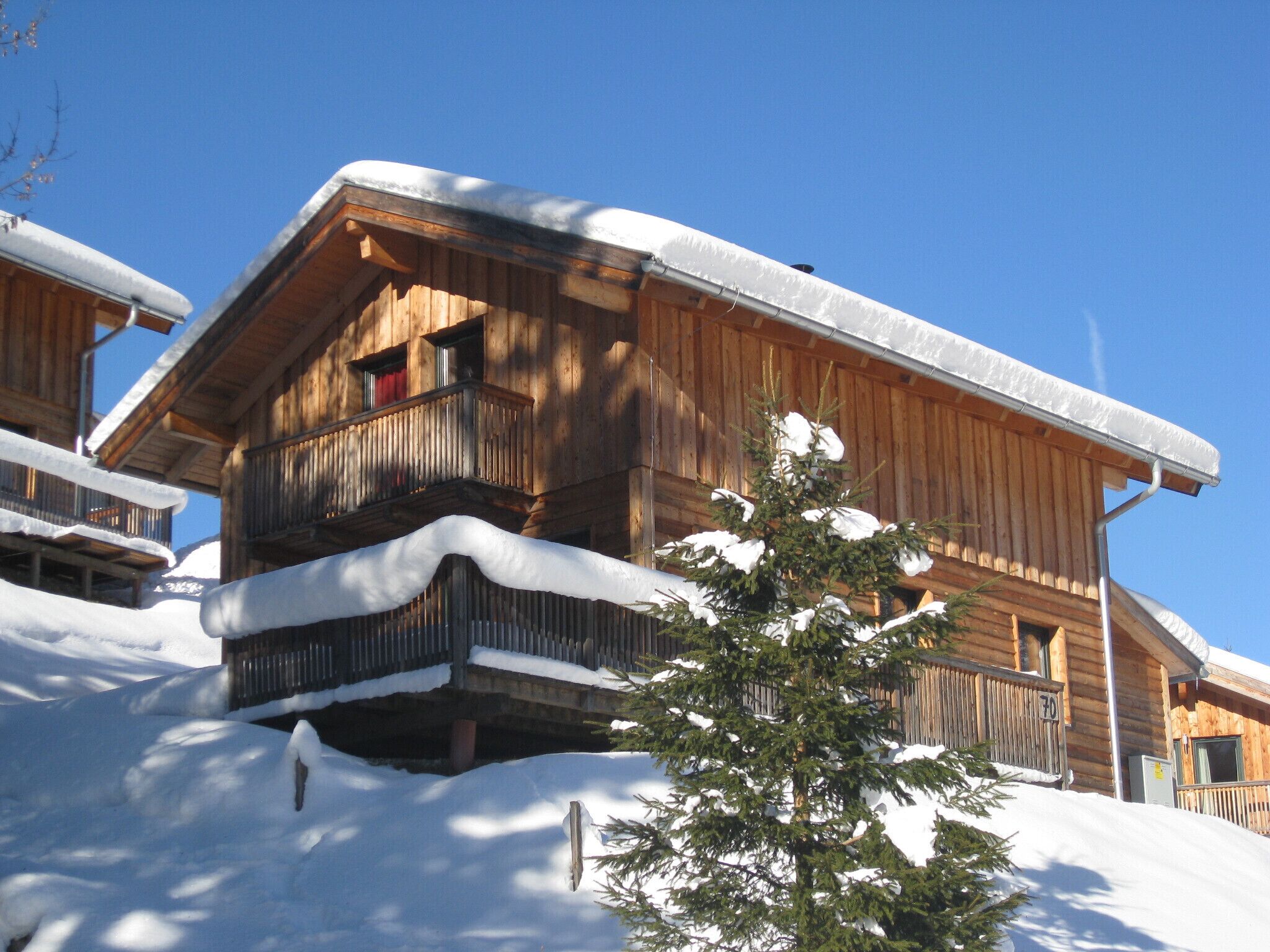 Eine Holzhütte mit Balkon und schneebedecktem Dach.