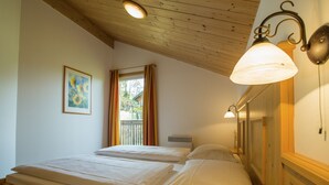 Una habitación con dos camas, una ventana con cortinas, un cuadro y una lámpara en la pared.