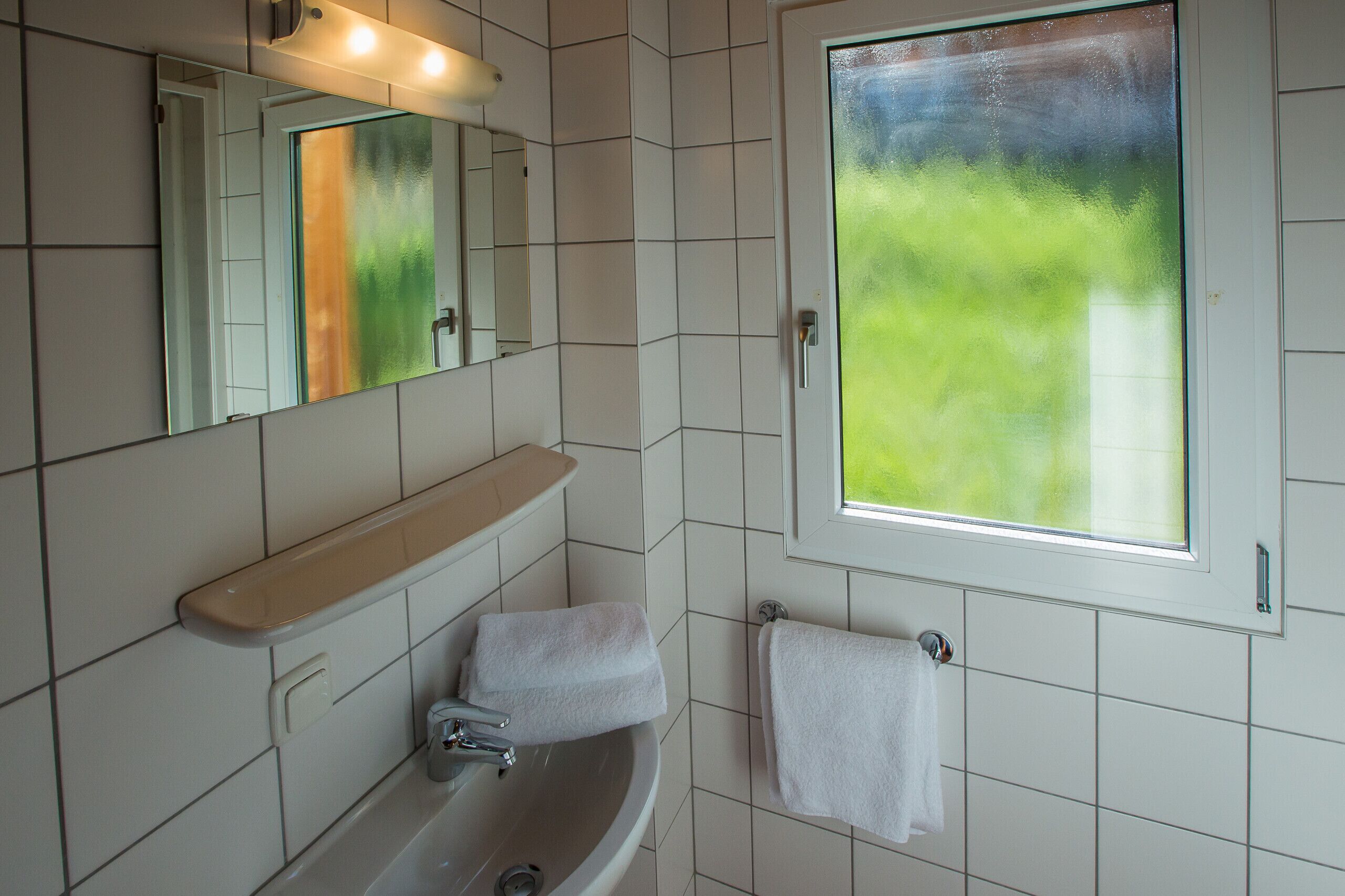 A bathroom with a sink, mirror, and window.