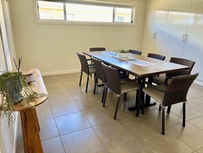 A conference room with a long table, wicker chairs, a potted plant, and a window with blinds. - Riptide - Pet friendly outside, WiFi (Robe)