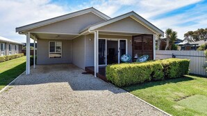 A modern single-story house with a covered porch, a gravel driveway, and a well-maintained lawn.