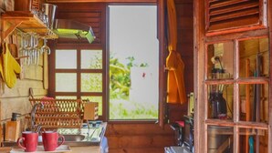 A rustic kitchen with wooden cabinets, a sink, and a window with a view of greenery.
