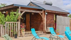 A wooden cabin with a porch, a pool, and lounge chairs.