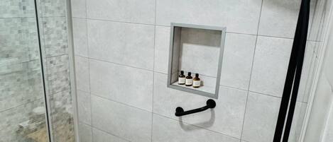 A modern shower area with a glass door, a handheld showerhead, and a handheld shower attachment.
