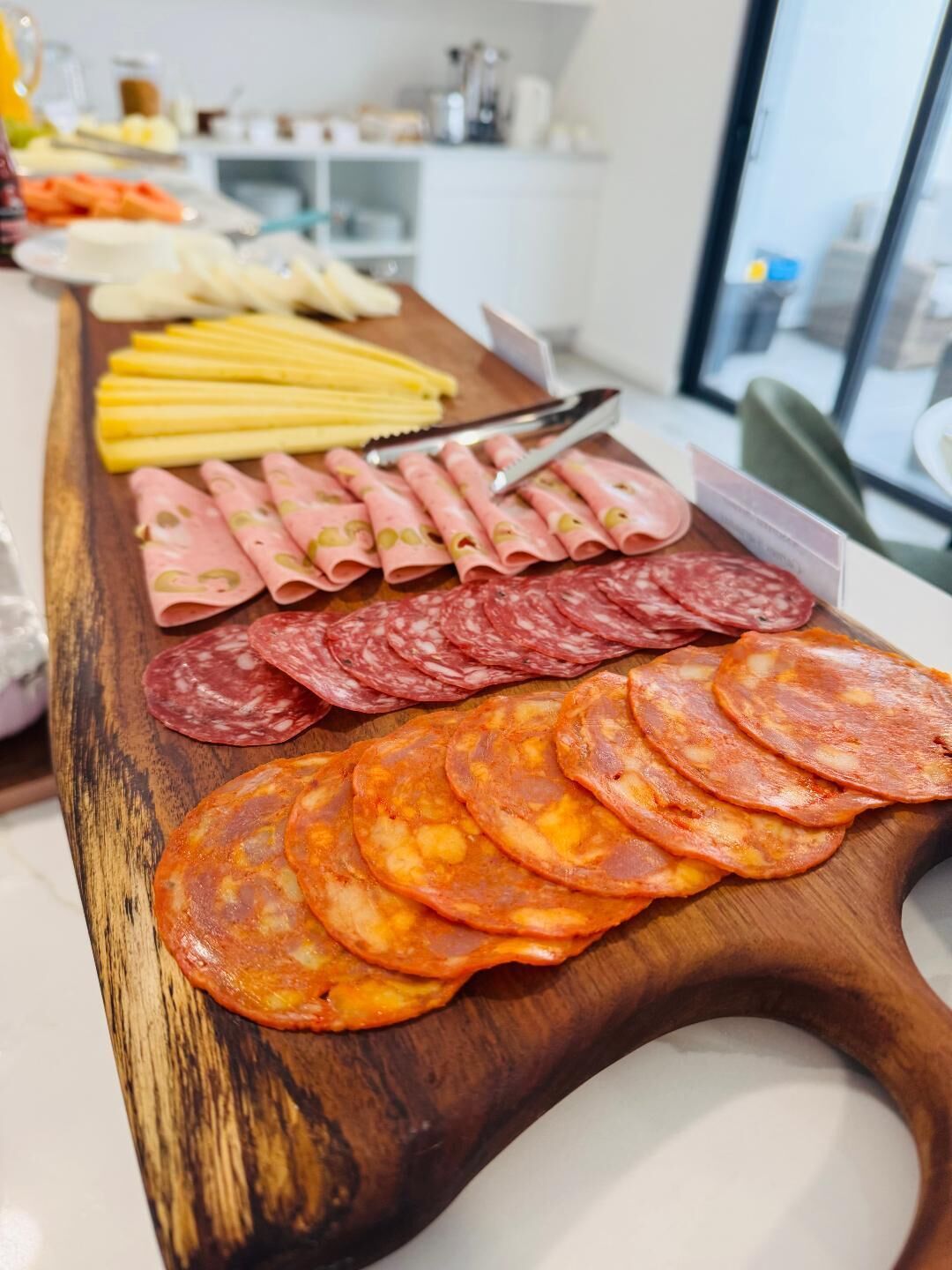 A wooden board with various types of cured meats and cheeses.