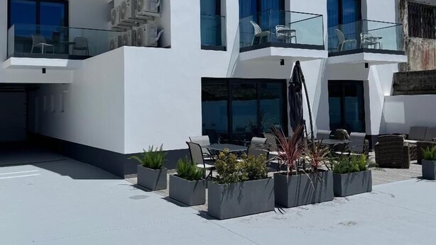 A modern two-story building with a flat roof, large windows, and a balcony with outdoor seating. - Bella Casa Bed & Breakfast (Ponta Delgada)