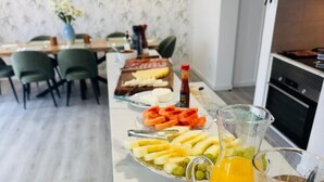 A breakfast setup with a fruit platter, sliced fruits, and two pitchers of orange juice on a table. - Bella Casa Bed & Breakfast (Ponta Delgada)