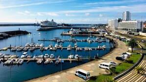 A marina with multiple boats docked, a large cruise ship, and a modern building complex in the background. - Bella Casa Bed & Breakfast (Ponta Delgada)
