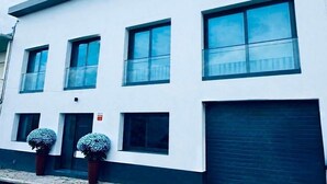 A modern building with a white facade, multiple windows, and a garage door. - Bella Casa Bed & Breakfast (Ponta Delgada)