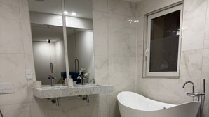 Une salle de bain moderne avec une baignoire sur pieds, des toilettes et un meuble-lavabo avec un miroir.