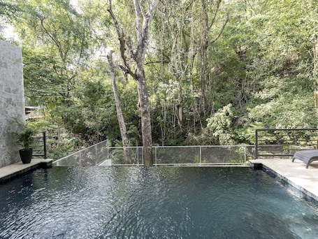 Una piscina al aire libre, sombrillas, sillones reclinables de piscina
