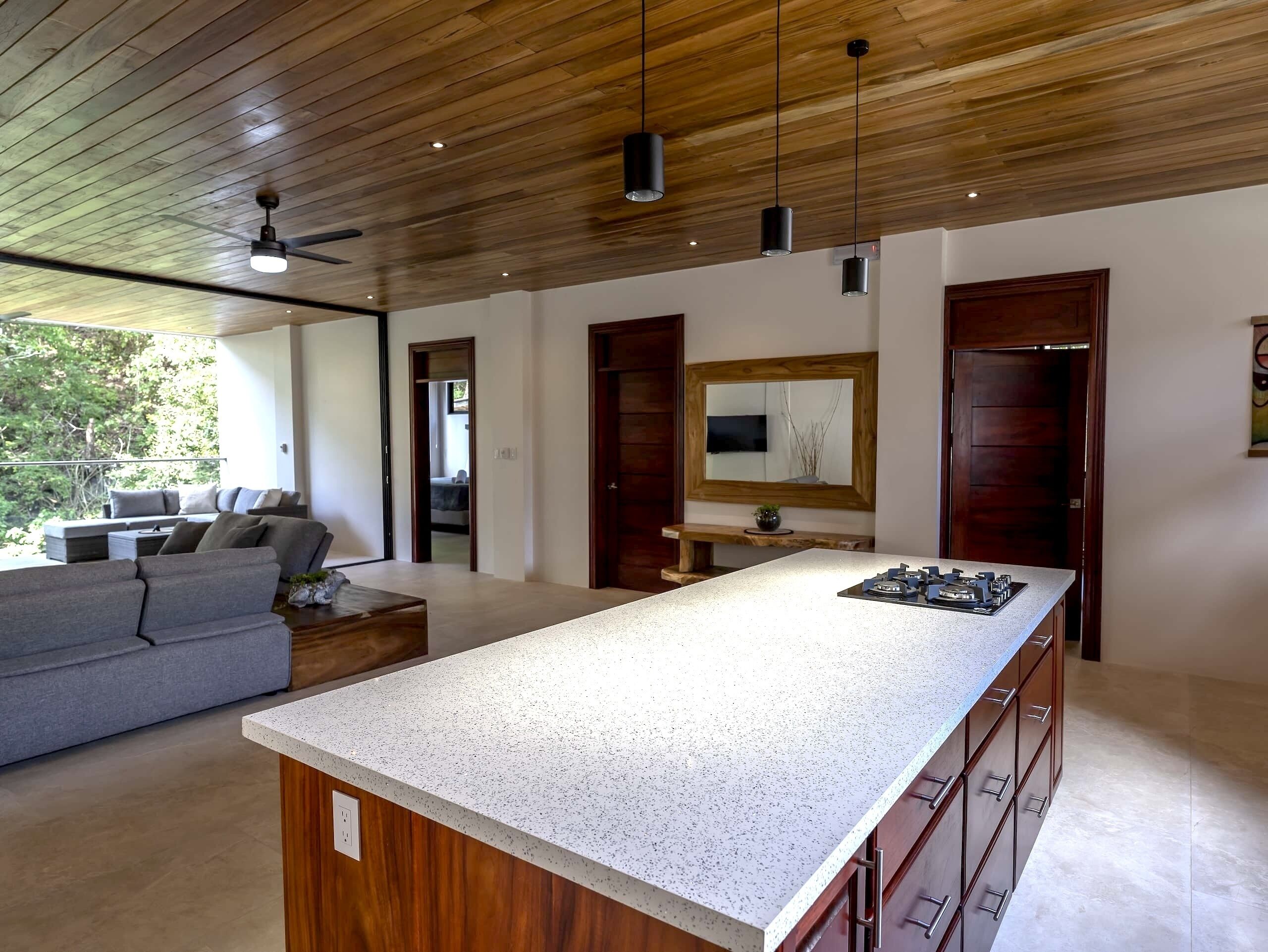 Una cocina moderna con una isla grande, armarios de madera y una estufa empotrada.