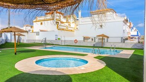 A swimming pool area with a hot tub, surrounded by artificial grass and a white building with balconies. - Casa Lodelia: sea and mountain views, nature and beaches just a stone's throw away (San Juan de los Terreros)