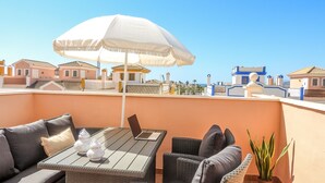 A balcony with outdoor furniture, a table, and a white umbrella. - Casa Lodelia: sea and mountain views, nature and beaches just a stone's throw away (San Juan de los Terreros)