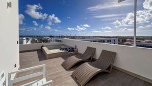 Una terraza en la azotea con sillones de descanso, una piscina pequeña y vistas panorámicas de la ciudad.