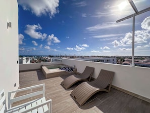 Una terraza en la azotea con sillones de descanso, una piscina pequeña y vistas panorámicas de la ciudad.