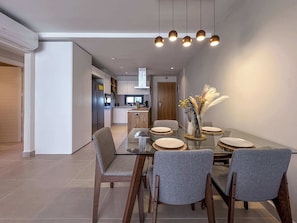 A modern dining area with a glass table, grey upholstered chairs, and a decorative vase.