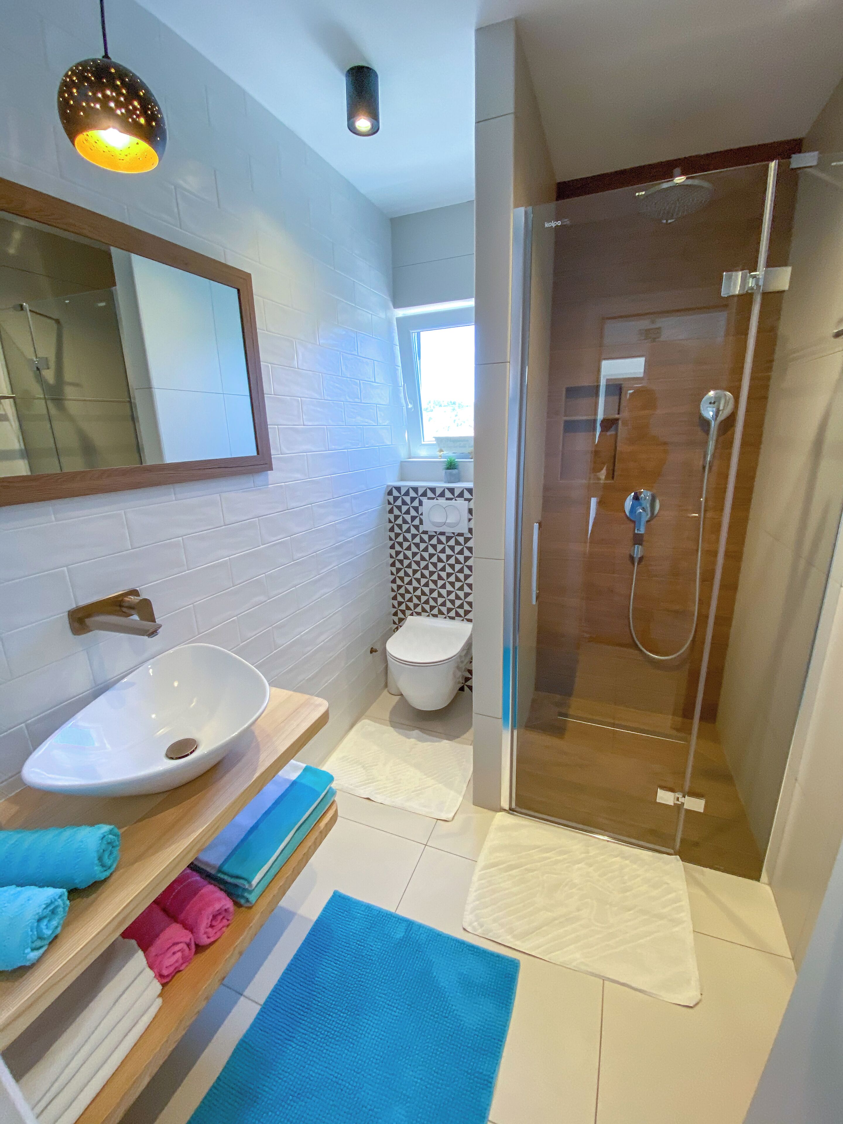 A modern bathroom with a white sink, a glass shower enclosure, and a mirror above the sink.