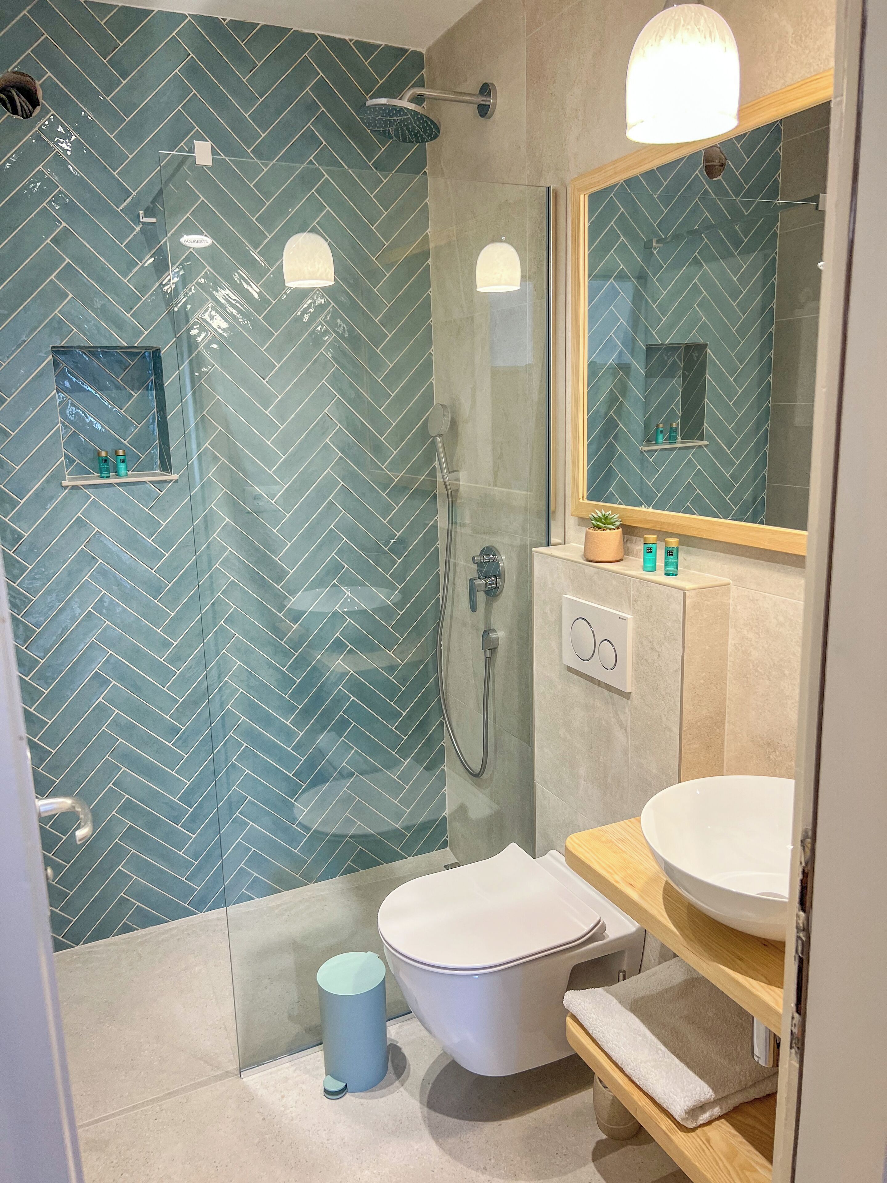 Une salle de bain moderne avec une douche à parois de verre, des toilettes blanches et un meuble-lavabo avec un miroir.