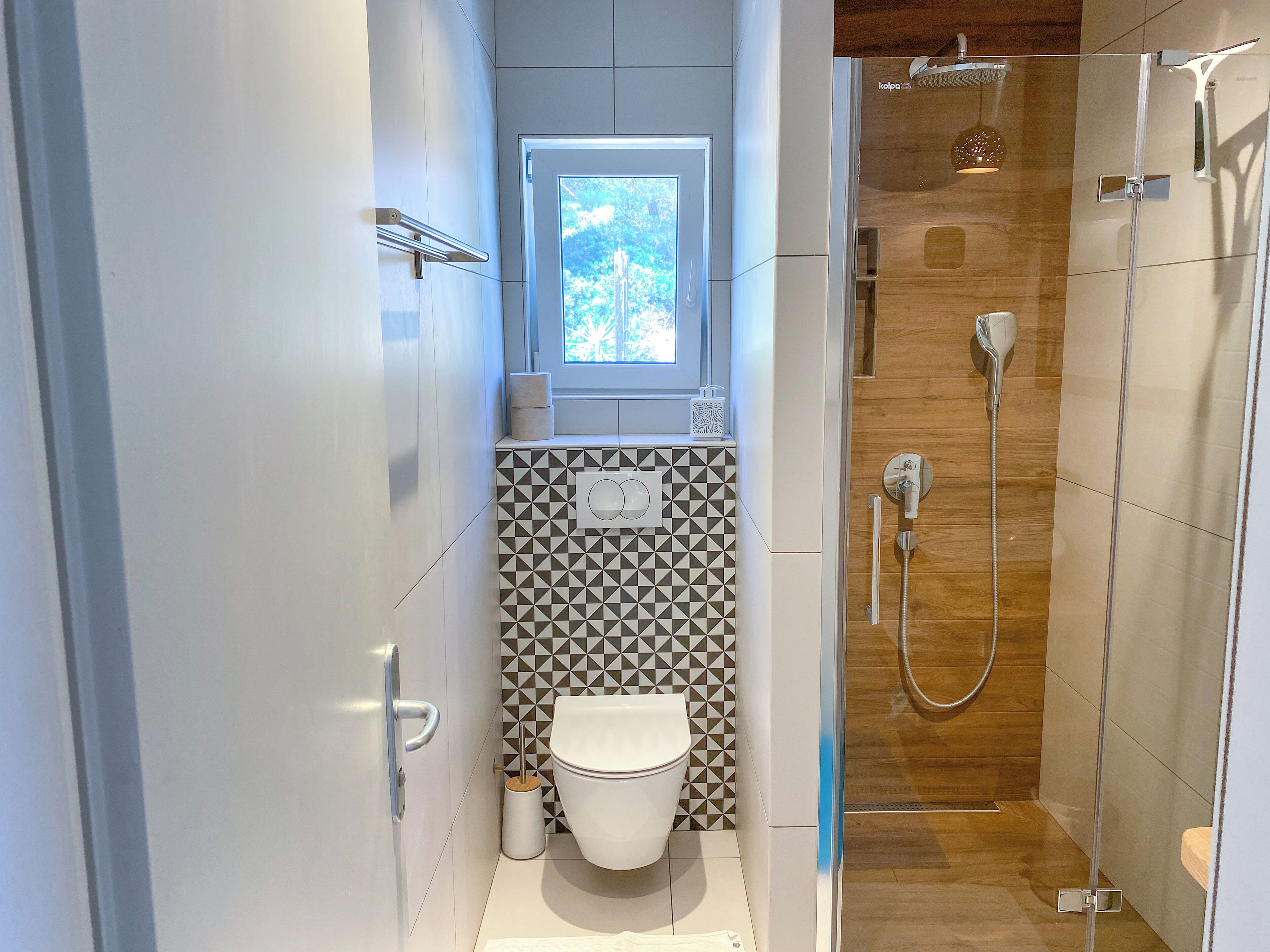 Een moderne badkamer met toilet, wastafel en douche.