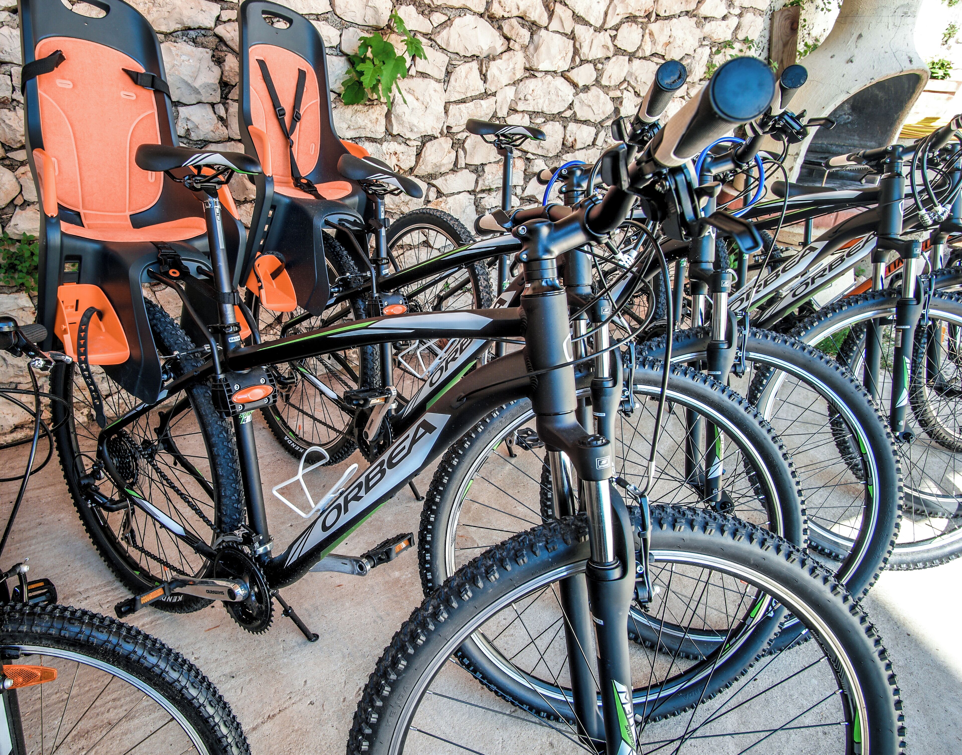 Una hilera de bicicletas estacionadas junto a una pared de piedra.