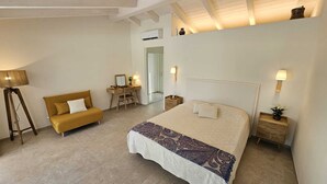 Un dormitorio con cama, sofá, escritorio y lámpara.